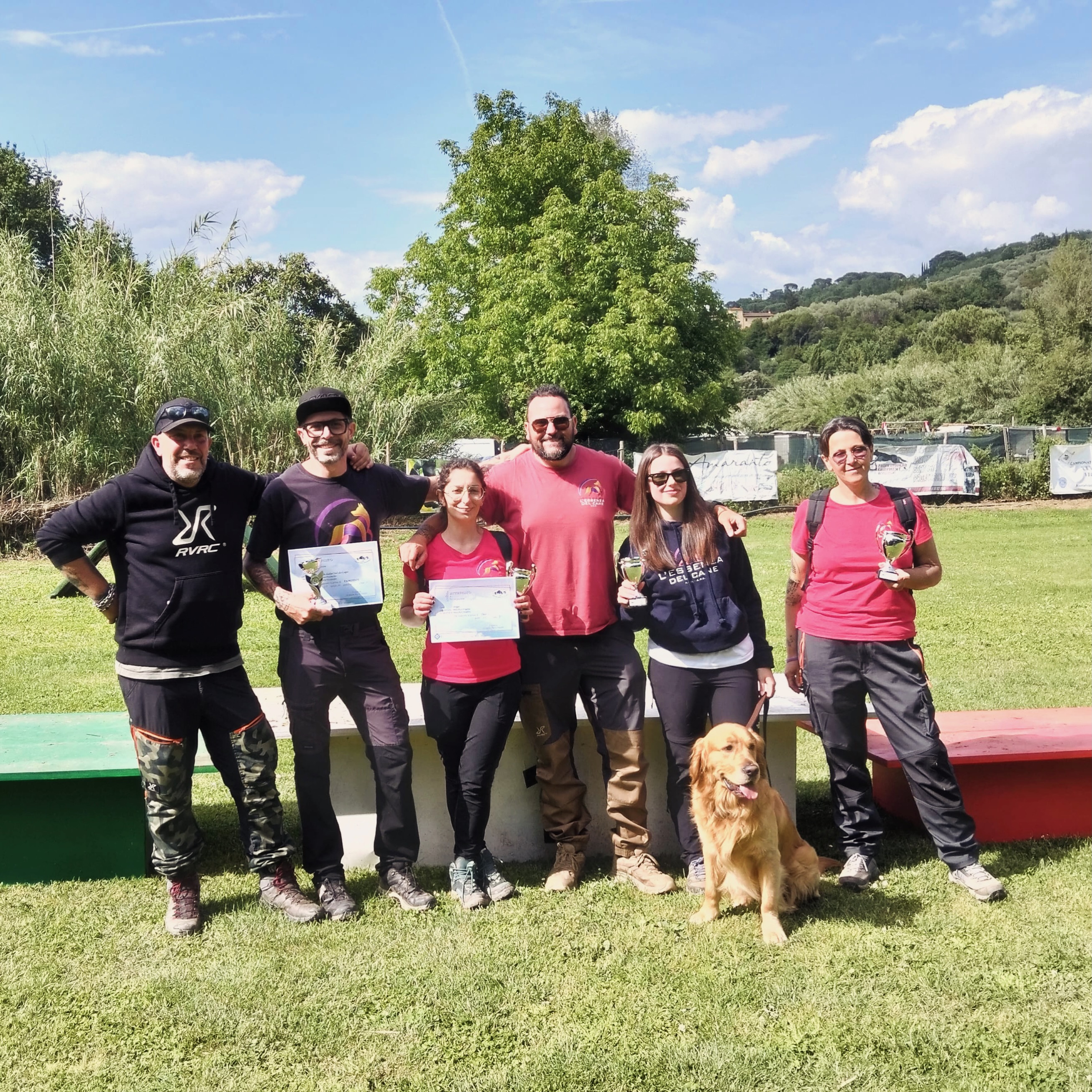 Un gruppo con attestati, coppe e un golden retriever